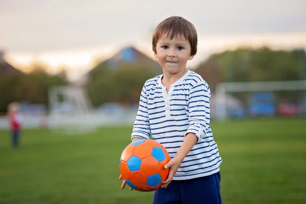 Menino pequeno jogando futebol e futebol, se divertindo outdo — Fotografia de Stock