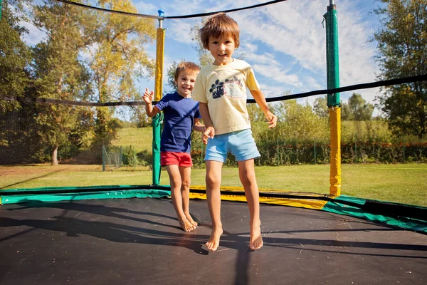 İki tatlı çocuk, kardeşler, trambolinde zıplayanlar, yaz mevsiminde, h — Stok fotoğraf