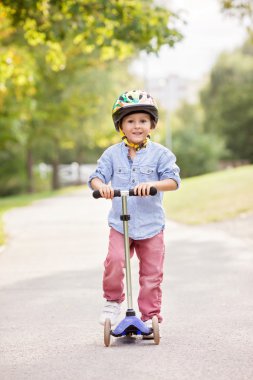 Cute boy, riding scooters, outdoor in the park, summertime
