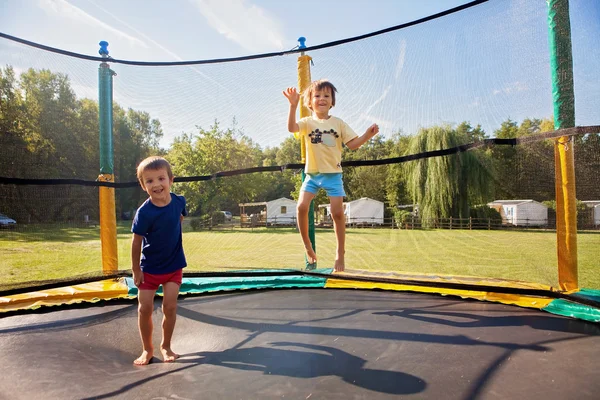 Two sweet kids, brothers, jumping on a trampoline, summertime, h — Stock Photo, Image