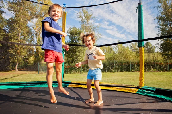 Dos niños dulces, hermanos, saltando en un trampolín, verano, h — Foto de Stock