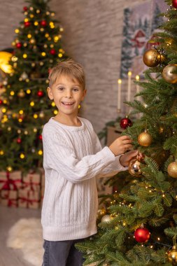 Sevimli anaokulu çocuğu, şöminenin önünde oturuyor, Noel hediyesini tutuyor ve evde kitap, eğlence ve mutluluk okuyor.
