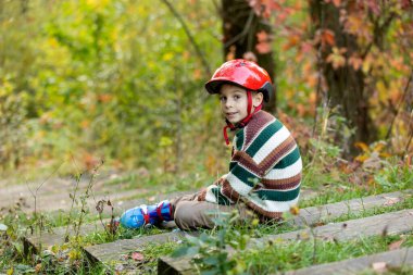Tatlı okul çocuğu, çocuk, paten kayıyor, sonbaharda sokakta paten kayıyor.