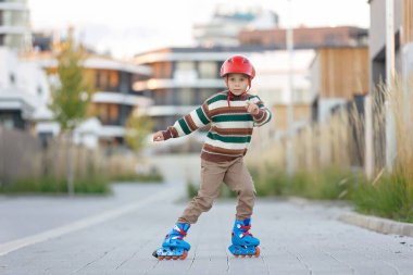 Tatlı okul çocuğu, çocuk, paten kayıyor, sonbaharda sokakta paten kayıyor.