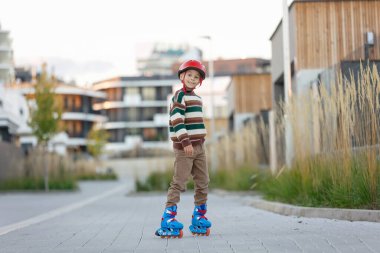 Tatlı okul çocuğu, çocuk, paten kayıyor, sonbaharda sokakta paten kayıyor.