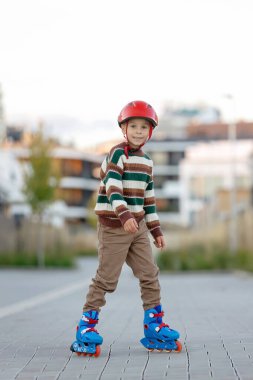 Tatlı okul çocuğu, çocuk, paten kayıyor, sonbaharda sokakta paten kayıyor.