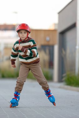 Tatlı okul çocuğu, çocuk, paten kayıyor, sonbaharda sokakta paten kayıyor.