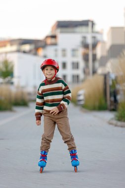 Tatlı okul çocuğu, çocuk, paten kayıyor, sonbaharda sokakta paten kayıyor.