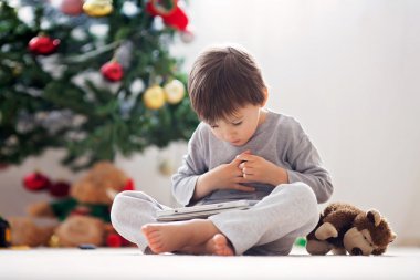 Sevimli küçük çocuk ve tablet üzerinde oynarken onun maymun oyuncak