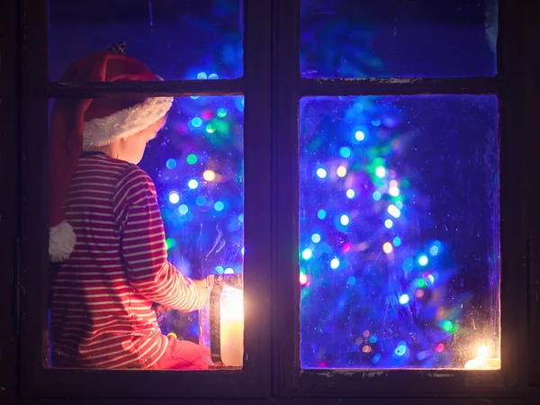 Niedlicher Junge, der auf einem Fensterschild sitzt, auf dem Handy spielt — Stockfoto