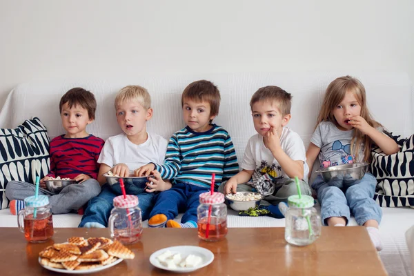 Cinco crianças doces, amigos, sentado na sala de estar, assistindo TV e — Fotografia de Stock