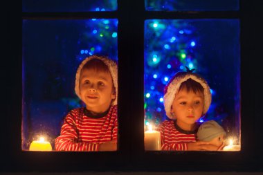 İki seeet çocuklar, bir pencere üzerinde oturmuş, açık arıyor, kış