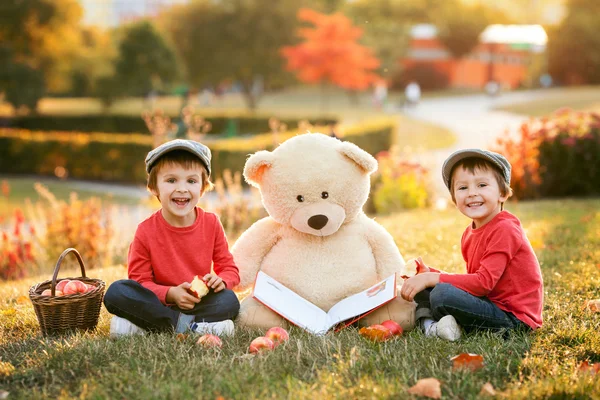 Dos adorables niños pequeños con su amigo oso de peluche en el parque —  Fotos de Stock