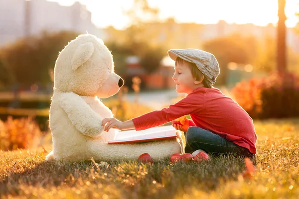 Roztomilý chlapeček s kamarádem medvídka v parku na su — Stock fotografie