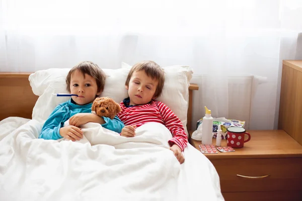 Two sick boys, brothers, lying down in bed with fever — Stock Photo, Image