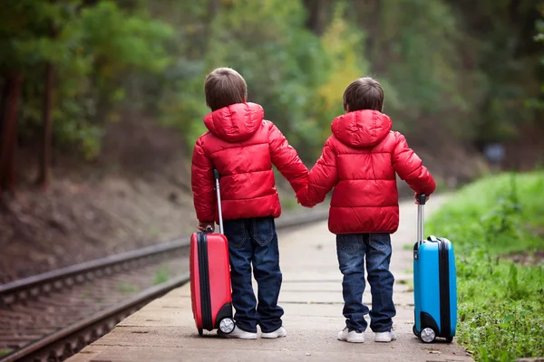 Dois meninos em uma estação ferroviária, esperando o trem com suitca — Fotografia de Stock