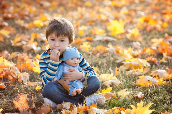 かわいい少年、秋の日、芝生の上に座っているパンケーキを食べて — ストック写真