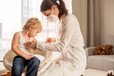 Küçük çocuk, sarışın çocuk, pediatri muayenehanesinden iğne oluyor, yıllık aşı..