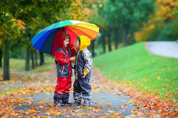 Duas crianças adoráveis, irmãos meninos, brincando no parque com umbrel — Fotografia de Stock