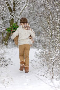 Çocuğum, karlı ormanda kış partisi veriyoruz. Genç bir çocuk, çay içiyor ve çam ağacının dallarıyla ilgileniyordu. Soğuk havada sıcak içecek, kar, soğuk ve açık havada ışık.