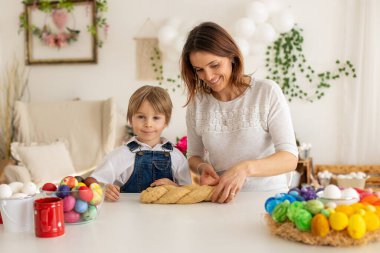 Küçük sarışın çocuk ve genç anne, Paskalya çörekleri için hamur hazırlıyorlar, fındıklı ve kuru meyveli paskalya ekmeği