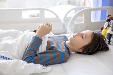Preteen child, boy, lying in hospital with fractured thoracic spine, vertebralis, mother sitting next to his bed