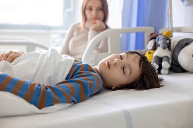 Preteen child, boy, lying in hospital with fractured thoracic spine, vertebralis, mother sitting next to his bed