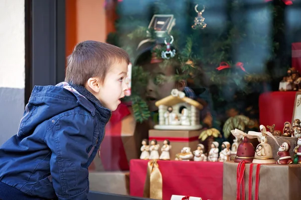 Милый мальчик, глядя в окно в магазине, украшенный fo — стоковое фото