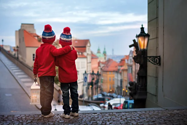 Two kids, standing on a stairs, holding a lantern, view of Pragu — Stock Photo, Image