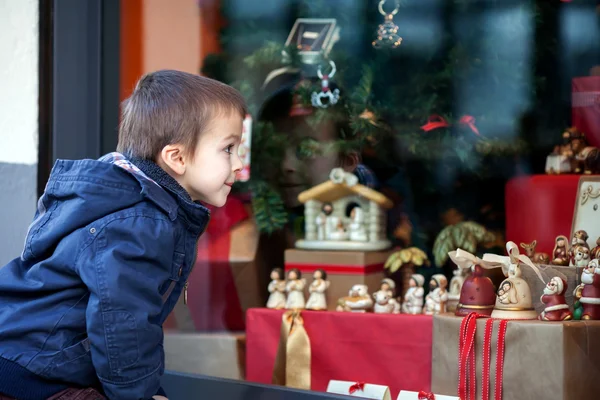 Słodki chłopczyk, patrząc przez okno w sklepie, zdobione fo — Zdjęcie stockowe