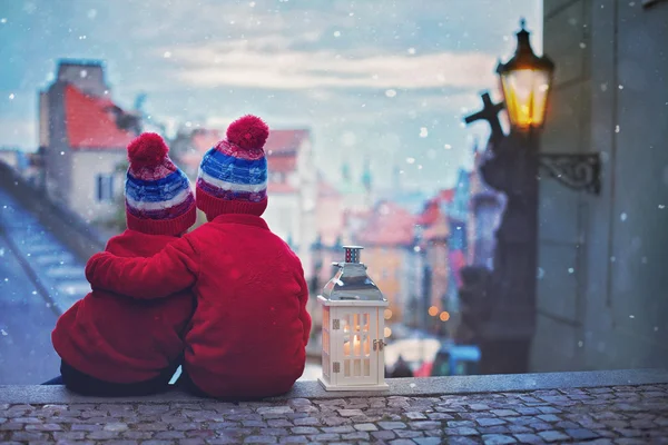 Two kids, standing on a stairs, holding a lantern, view of Pragu — Stock Photo, Image