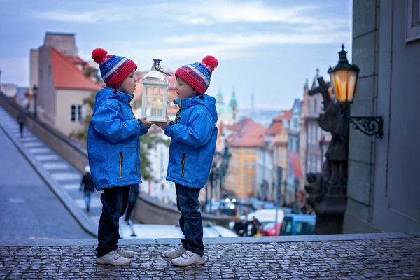 Zwei Kinder, die auf einer Treppe stehen, eine Laterne in der Hand, Blick auf pragu — Stockfoto