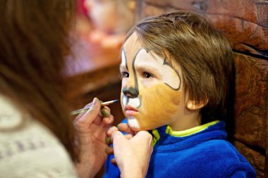 Bir aslan olarak boyalı yüzü olan küçük çocuk