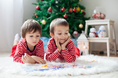 İki erkek, Noel ağacı önünde bir kitap okuma