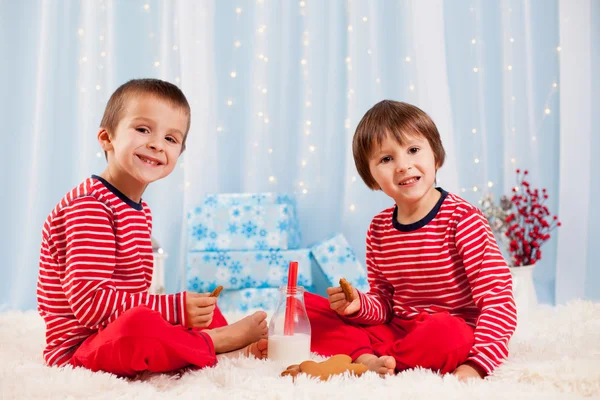 Dos niños felices comiendo galletas en Navidad y bebiendo leche —  Fotos de Stock