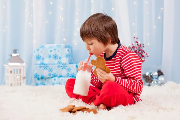 Niedlicher kleiner glücklicher Junge, isst Kekse und trinkt Milch, wartet — Stockfoto