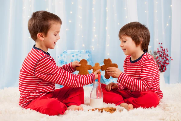两个快乐的孩子们在圣诞节吃饼干、 喝牛奶 — 图库照片
