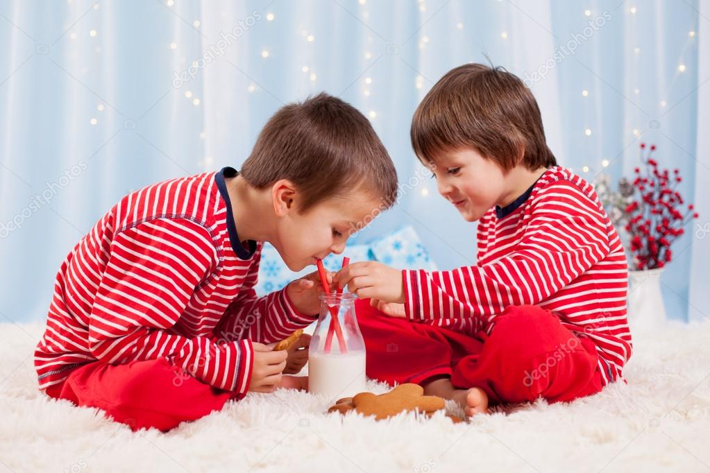 Two happy children eating cookies at christmas and drinking milk