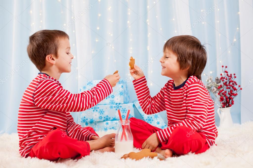 Two happy children eating cookies at christmas and drinking milk