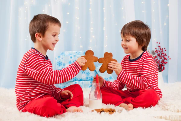 Duas crianças felizes comendo biscoitos no Natal e bebendo leite — Fotografia de Stock