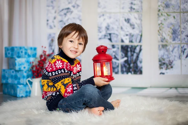 Doce criança, segurando lanterna em casa em um dia nevado — Fotografia de Stock