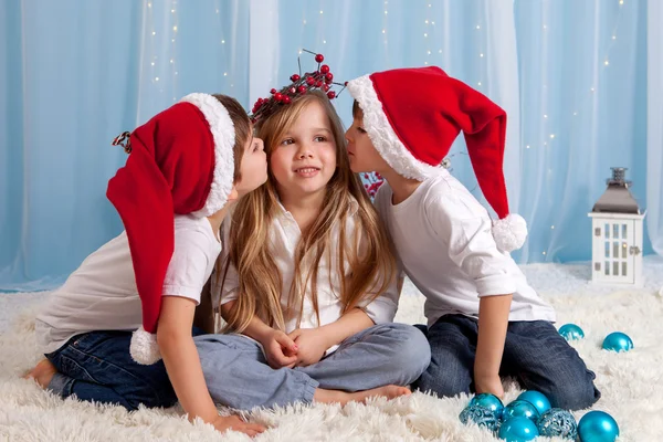 Two little twin brothers, giving a kiss to their sister, Christm — Stock Photo, Image