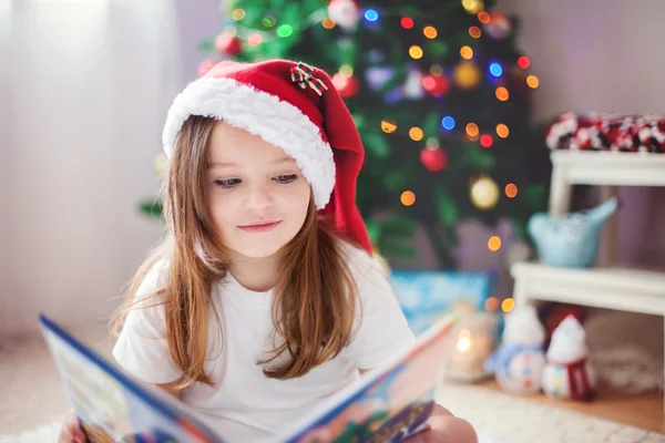 Όμορφη κοπέλα, διαβάζοντας ένα βιβλίο μπροστά από το χριστουγεννιάτικο δέντρο — Φωτογραφία Αρχείου