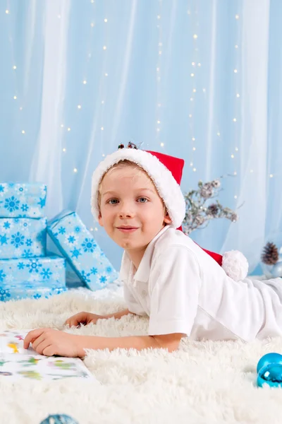 Dulce chico, leyendo un libro sobre Navidad, decoración a su alrededor —  Fotos de Stock
