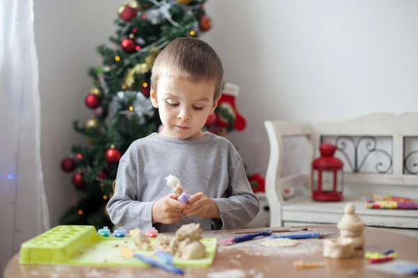 Petit garçon mignon, jouant avec la pâte à modeler, moulant des figures à la maison à Noël — Photo
