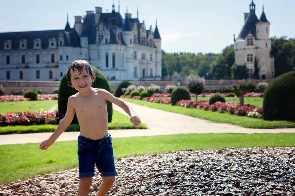 Lindo niño, jugando bajo la lluvia frente a un castillo en Fra — Foto de Stock