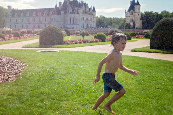 Cute little boy, playing in the rain in front of a castle in Fra