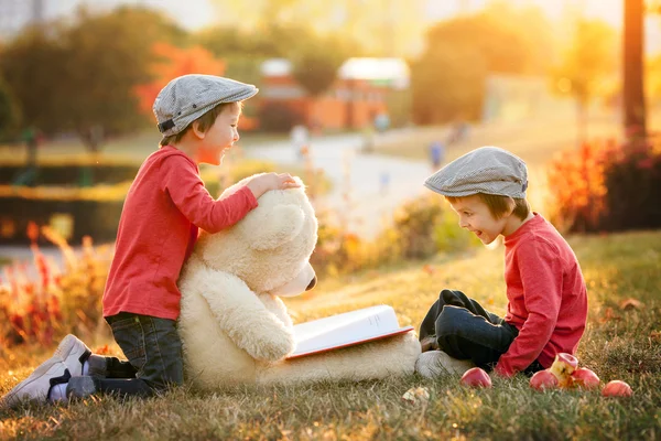 Dos adorables niños pequeños con su amigo oso de peluche en el parque —  Fotos de Stock