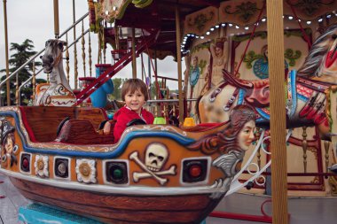 Sweet boy, riding in a train on a merry-go-round, carousel attra
