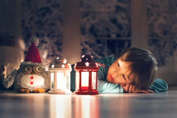 Beautiful little boy, lying down on the floor, looking at candle — Stock Photo, Image